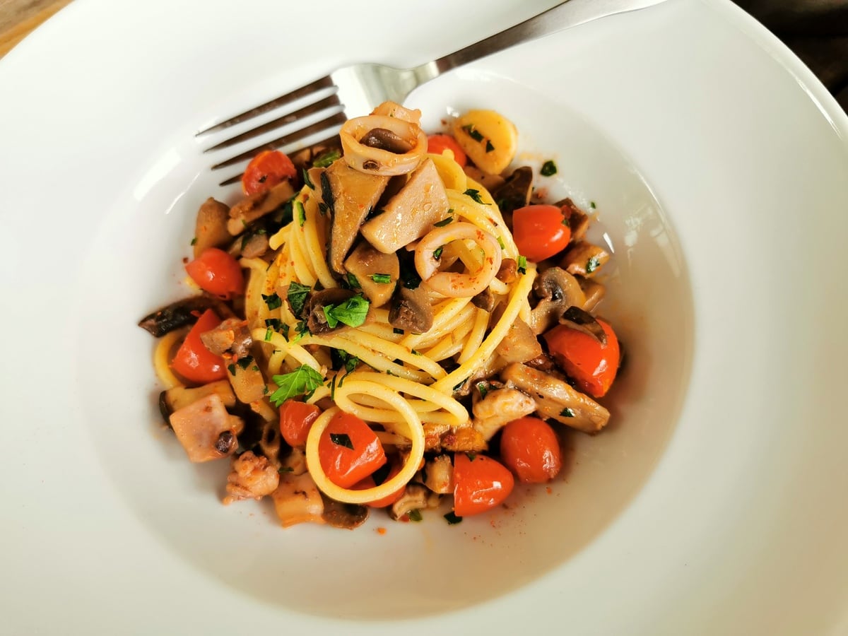 Spaghetti mare e monti from Marche garnished with sliced parsley.